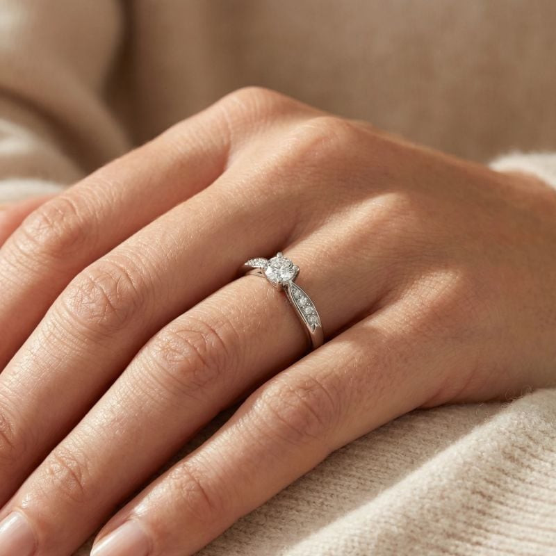 Bague solitaire Phebus oxyde de zirconium blanc portée par une femme sur un pull beige