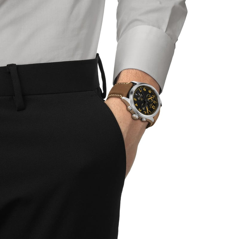 Homme portant la montre Tissot Chrono L 42mm à cadran noir dans un cadre de vie en plein air