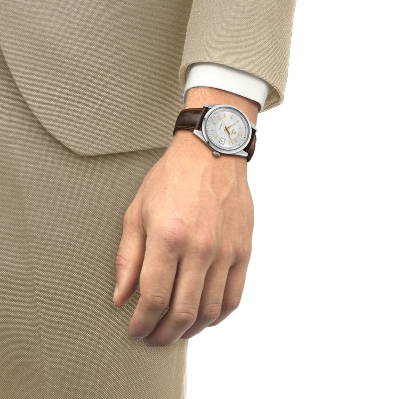 Poignet d'un homme portant la montre Tissot Visodate 39mm avec bracelet en cuir brun, associée à une