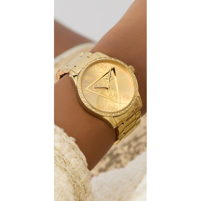 Montre Analogique GUESS Collection Roxy bracelet acier doré portée au poignet d'une femme élégante