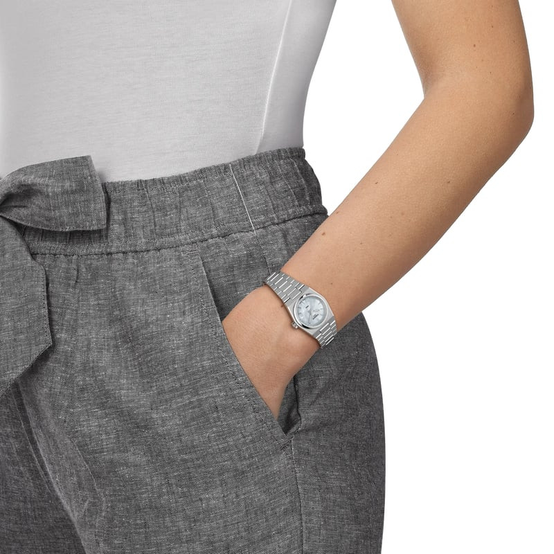 Femme portant la Montre Analogique TISSOT Collection PRX bracelet acier gris au poignet