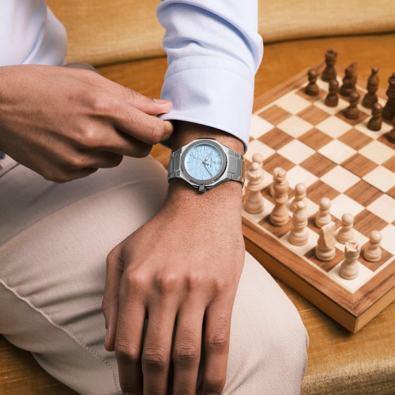 Homme portant la montre Pierre Lannier Graphite avec cadran bleu glacier, ajustant sa manchette, éch
