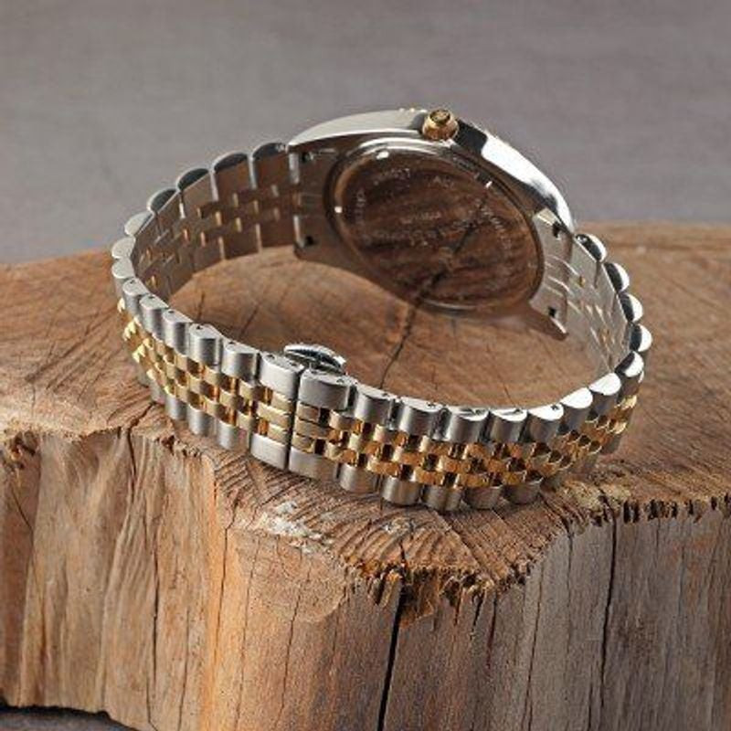 Montre Jacques Du Manoir Inspiration à bracelet bicolore exposée sur une bûche en bois rustique