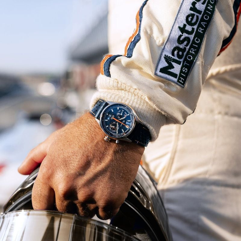 Montre Depancel Autosport Blue au poignet d'un pilote, à côté d'un casque et d'une combinaison de co