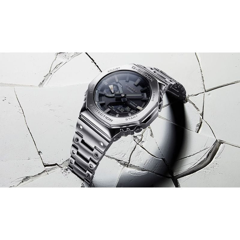 Montre Casio G-Shock en métal posée sur du béton blanc fissuré, illustrant sa résistance aux chocs