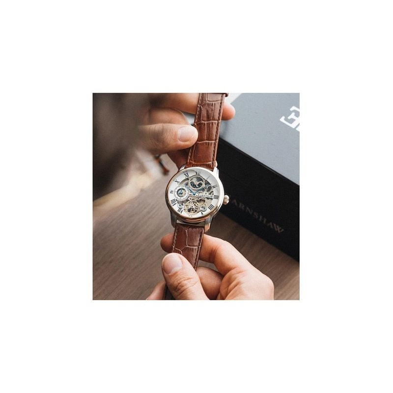 Homme tenant la montre automatique Thomas Earnshaw Longitude ES-8006-08 bracelet cuir marron près de