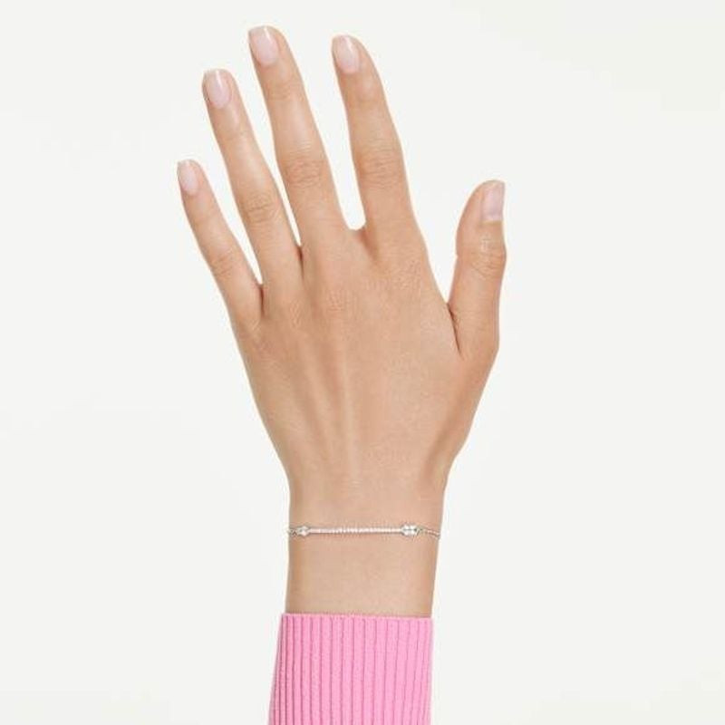 Poignet d'une femme portant le bracelet Swarovski Idyllia flèche en cristaux blancs, sur une manche 