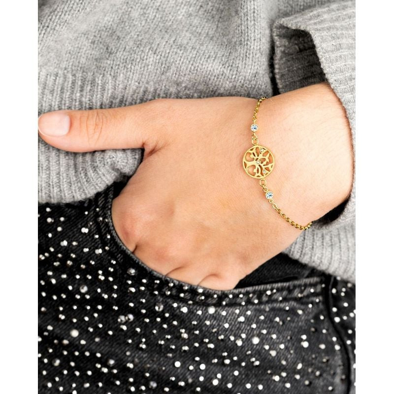 Poignet d'une femme portant un bracelet arbre de vie doré avec un pull en maille gris et un haut noi