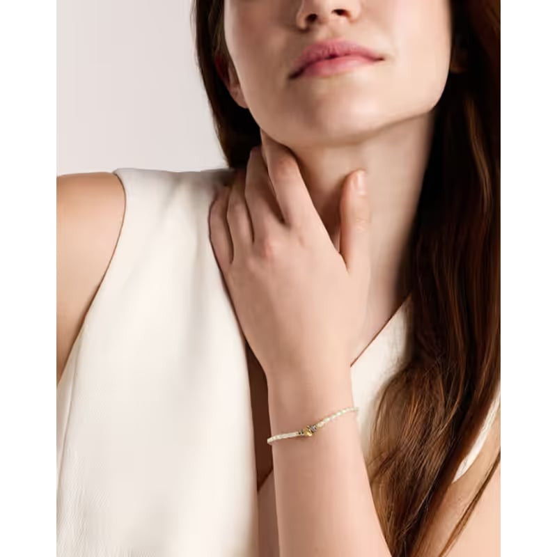 Femme en top blanc portant le bracelet Fossil Harlow à son poignet dans un portrait lifestyle