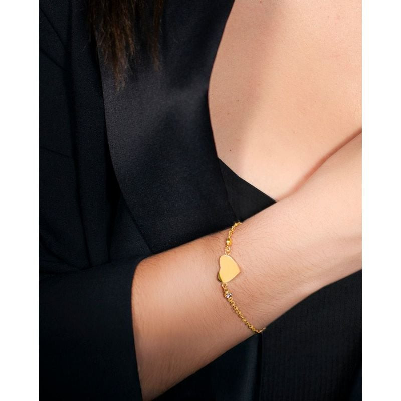 Femme portant un bracelet cœur Lotus Style doré au poignet avec un blazer noir, photo bijou lifestyl