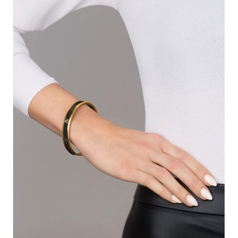 Poignet d'une femme portant le bracelet jonc FREY WILLE Midnight Black à liserés dorés, avec un pull