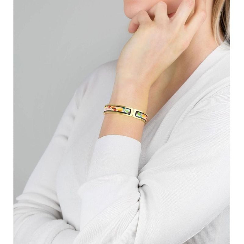 Modèle portant le bracelet clip Ballerina FREYWILLE Joy au poignet, jonc fin doré à l'émail coloré