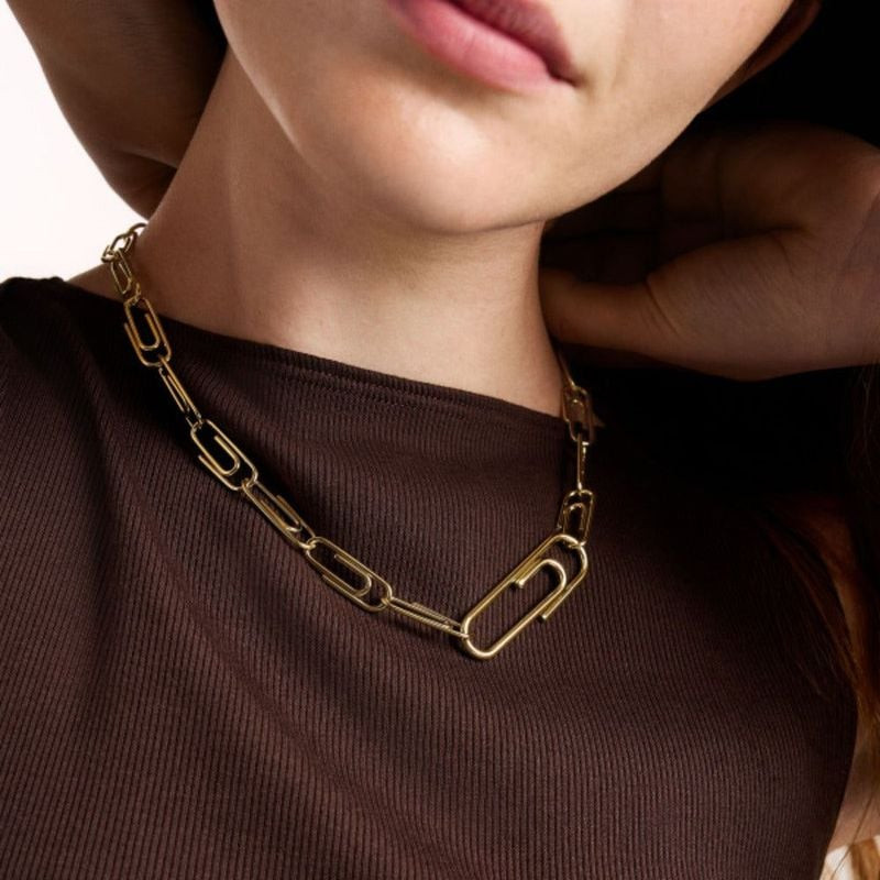 Mannequin portant le collier chaîne paperclip doré Fossil sur un haut côtelé marron