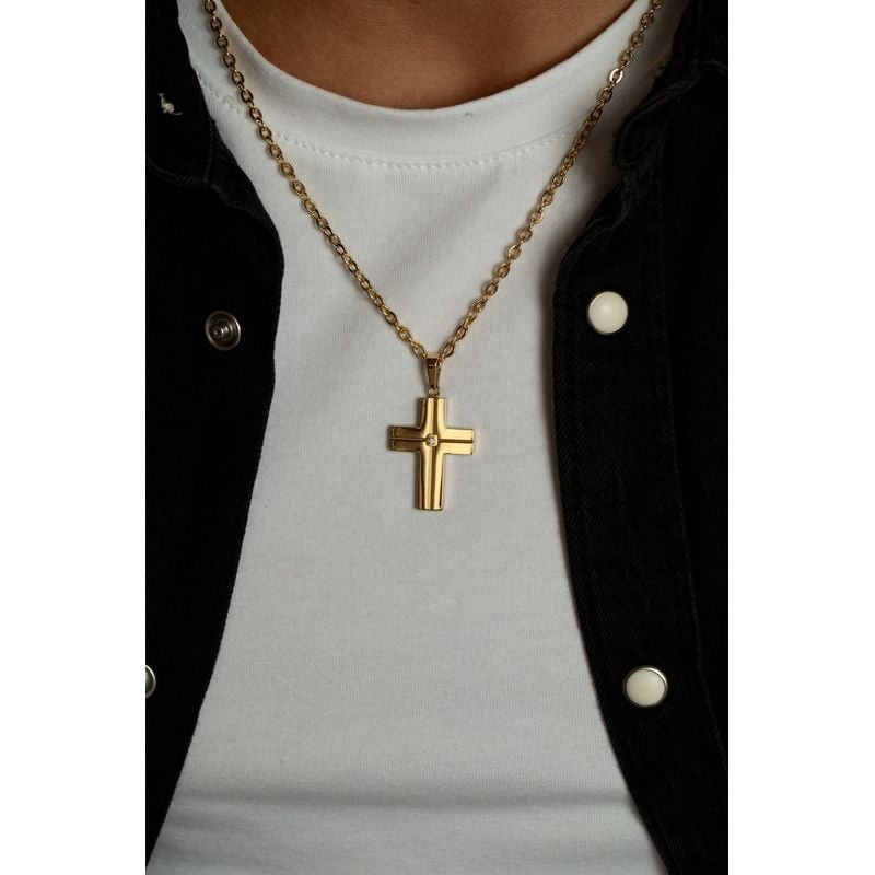 Gros plan du collier croix Phebus doré avec diamant porté sur un t-shirt blanc et une veste en jean 