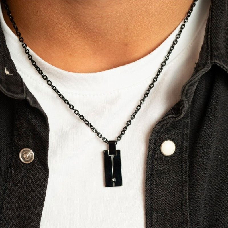 Gros plan du collier pendentif PHEBUS en acier noir serti d'un diamant porté sur un t-shirt blanc