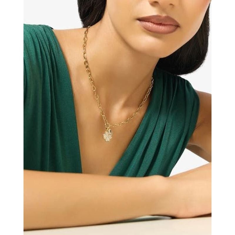 Collier Guess Love Bites Trèfle Pavé Acier Doré porté sur une tenue élégante, effet scintillant.