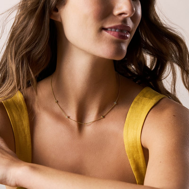 Femme portant le Collier Fossil Sutton Heartbeat Laiton Doré, un bijou délicat et raffiné.