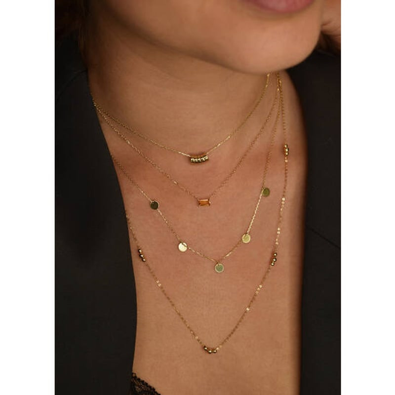 Mannequin portant le collier Medina Citrine Jackie Gold or 14 carats, superposé à d'autres chaînes f