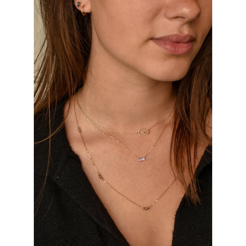 Modèle portant le collier Jackie Gold Medina en or 14 carats améthyste, superposé à deux chaînes dor