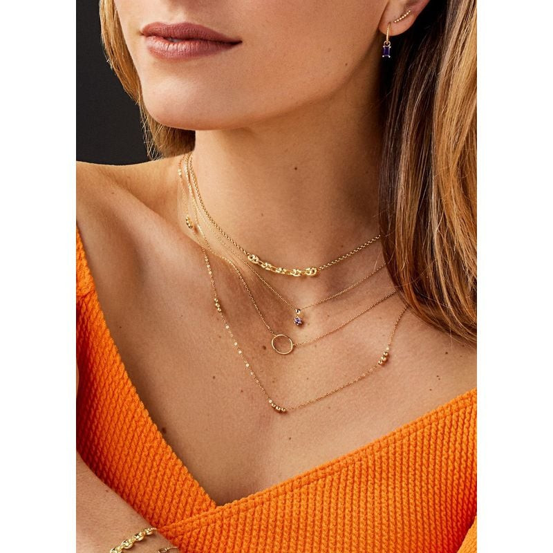 Mannequin portant le collier Jackie Gold 14 carats à pendentif cercle, superposé à d'autres colliers