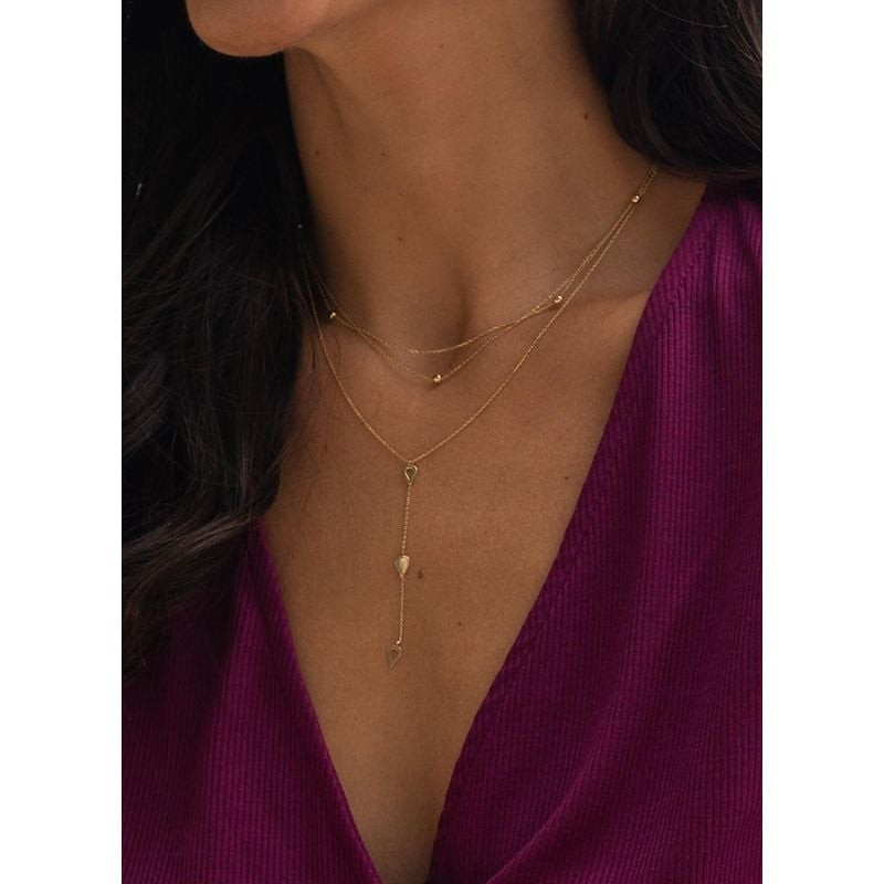 Modèle portant le collier Jackie Gold 14K Y sur un haut magenta, pendentif goutte visible sur la poi