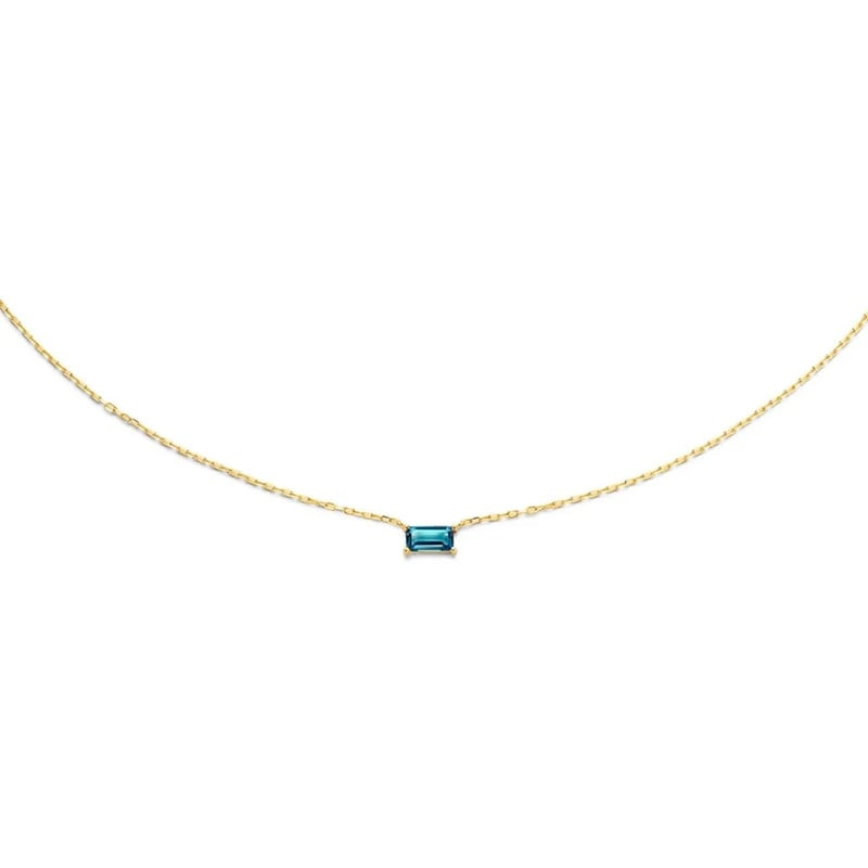 Gros plan du collier Jackie Gold Medina montrant la topaze bleue taille baguette sertie sur or jaune