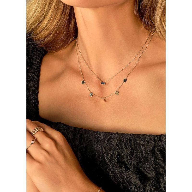 Colliers dorés superposés au cou d'une femme, cœurs et pendentif Jackie Gold Medina topaze bleue sur