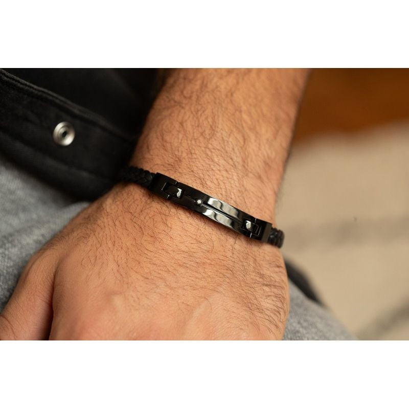Bracelet Phebus en cuir noir et diamant porté au poignet d'un homme, veste en cuir noir et denim gri