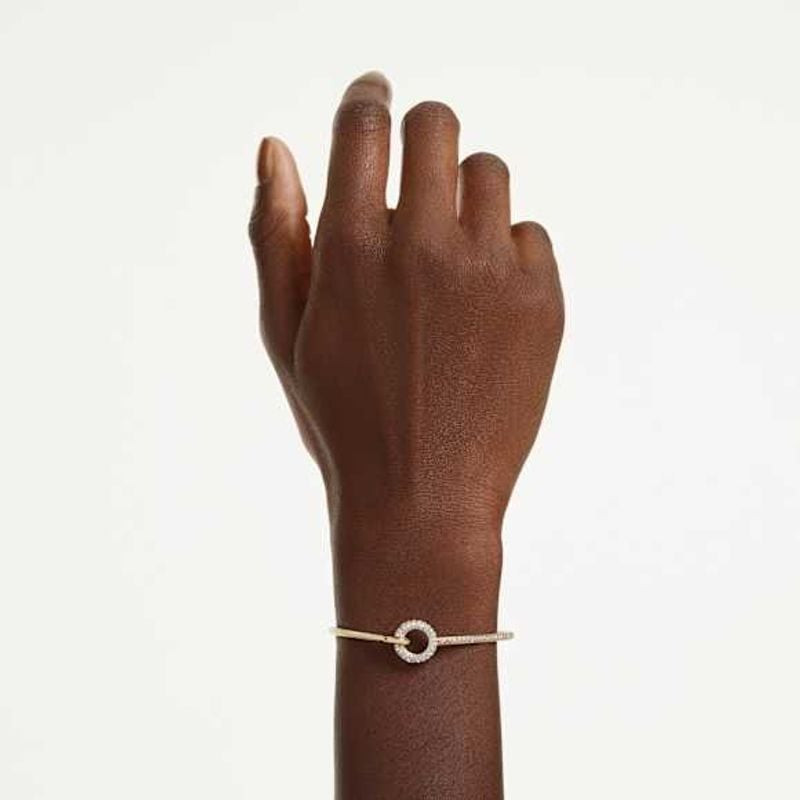 Poignet d'un mannequin portant le bracelet Swarovski Dextera doré et son motif circulaire de cristau