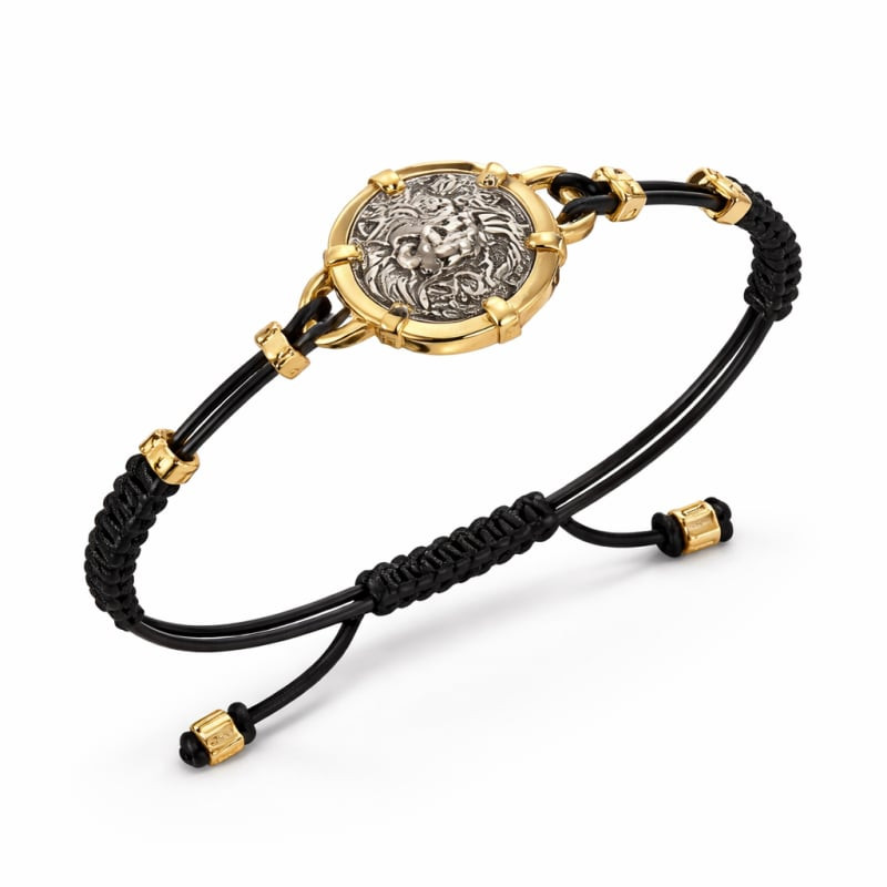 Bracelet GUESS Lion Legacy vue inclinée, tête de lion argentée sur cadre doré, cordon noir et fermoi