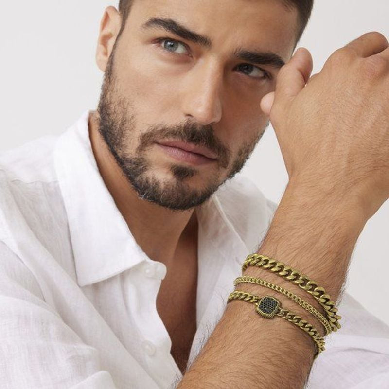 Homme portant une chemise en lin et des bracelets Guess dorés empilés, dont la gourmette Urban Code 