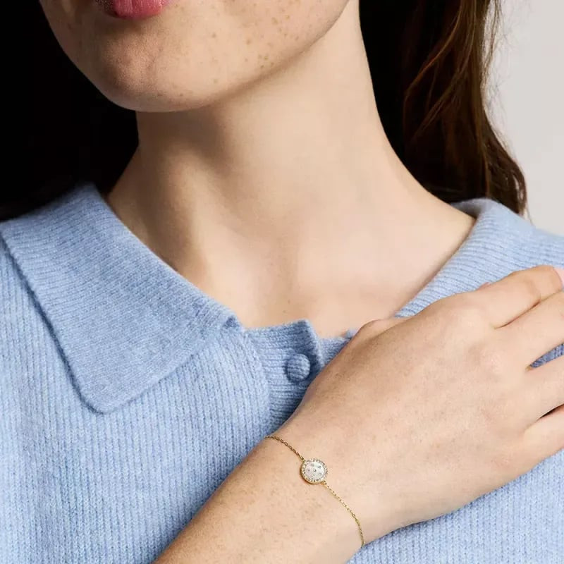 Femme portant le bracelet Fossil Merrit Northlight doré avec station en nacre et cristaux au poignet