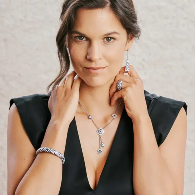 Femme en haut noir portant un bracelet jonc aztèque UNA STORIA en argent, avec collier et boucles d'