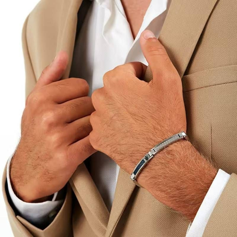 Homme en blazer beige ajustant sa manche, portant le bracelet Maserati Iconic bleu en acier au poign