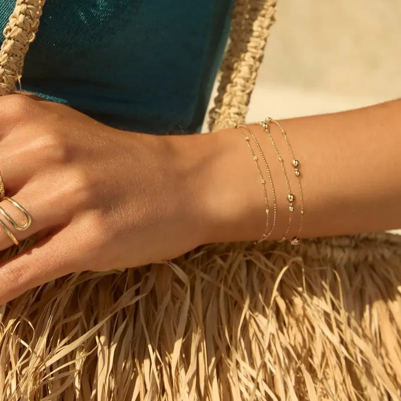 Bracelets Jackie Gold tête de lion 14 carats et billes dorées au poignet d'une femme, style extérieu