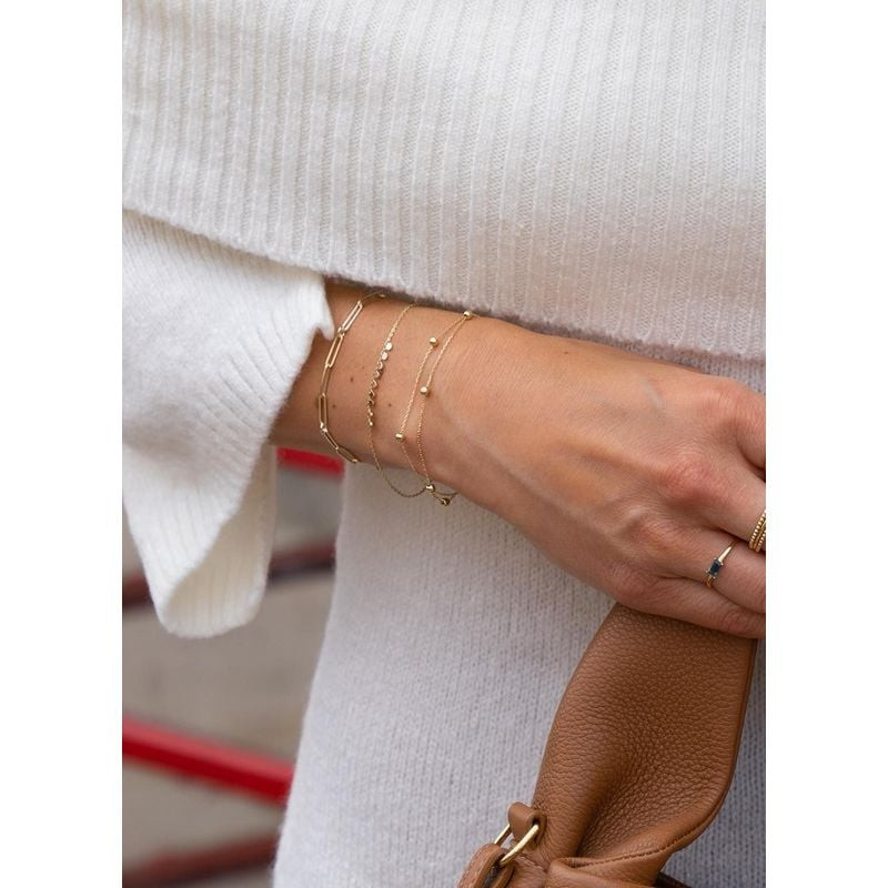 Femme portant le bracelet Jackie Gold Double Bulles en or 14 carats avec d'autres bracelets en or au