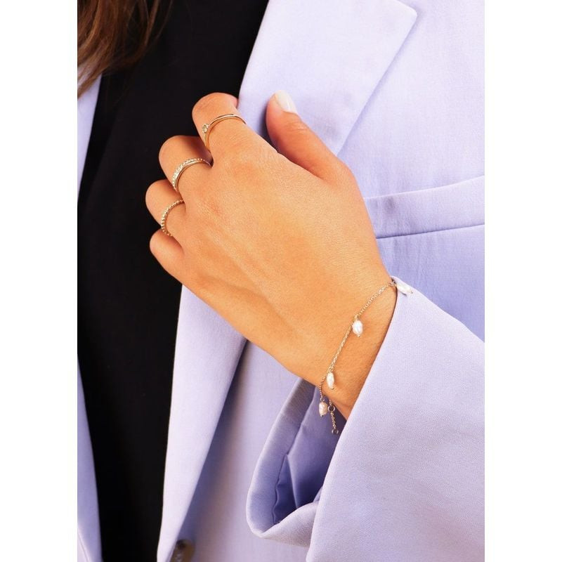 Gros plan du bracelet à perles d'eau douce en or 14 carats au poignet d'une femme, bagues en or et b