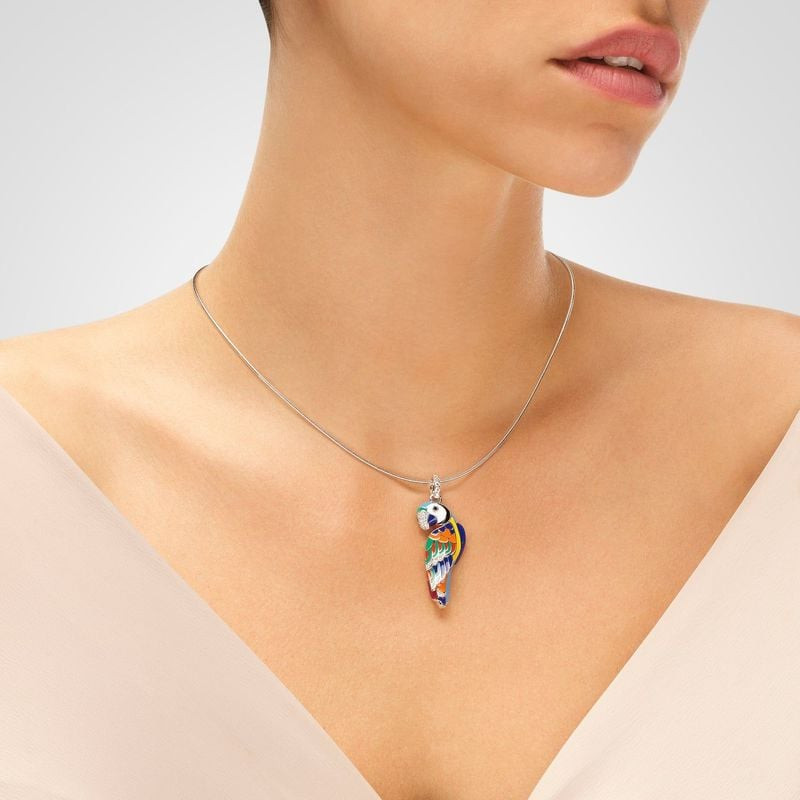 Pendentif perroquet LoveBird Una Storia porté sur une fine chaîne à câble argent, sur un top blanc, 