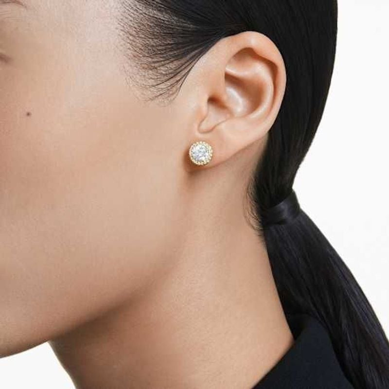 Boucles d'oreilles clous Swarovski Una Angelic Cristal Doré portées sur un lobe, look élégant du quo
