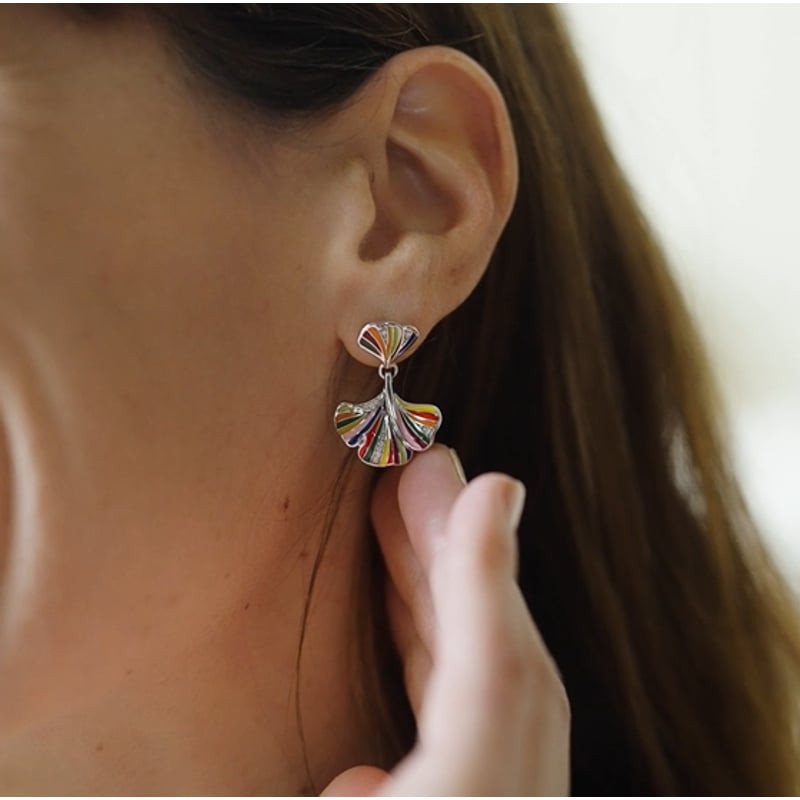 Détail en gros plan de la boucle d'oreille Ginkgo UNA STORIA avec une main touchant délicatement le 