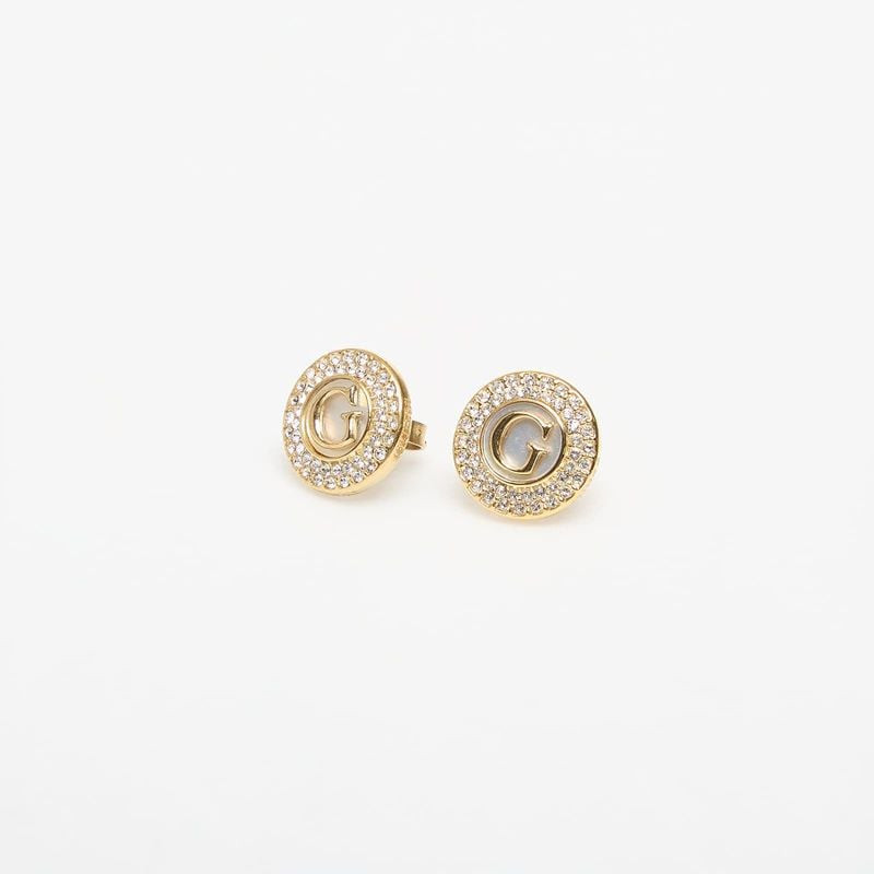 Vue rapprochée des clous d'oreilles GUESS G Talisman dorés, contour pavé de cristaux et logo G en na