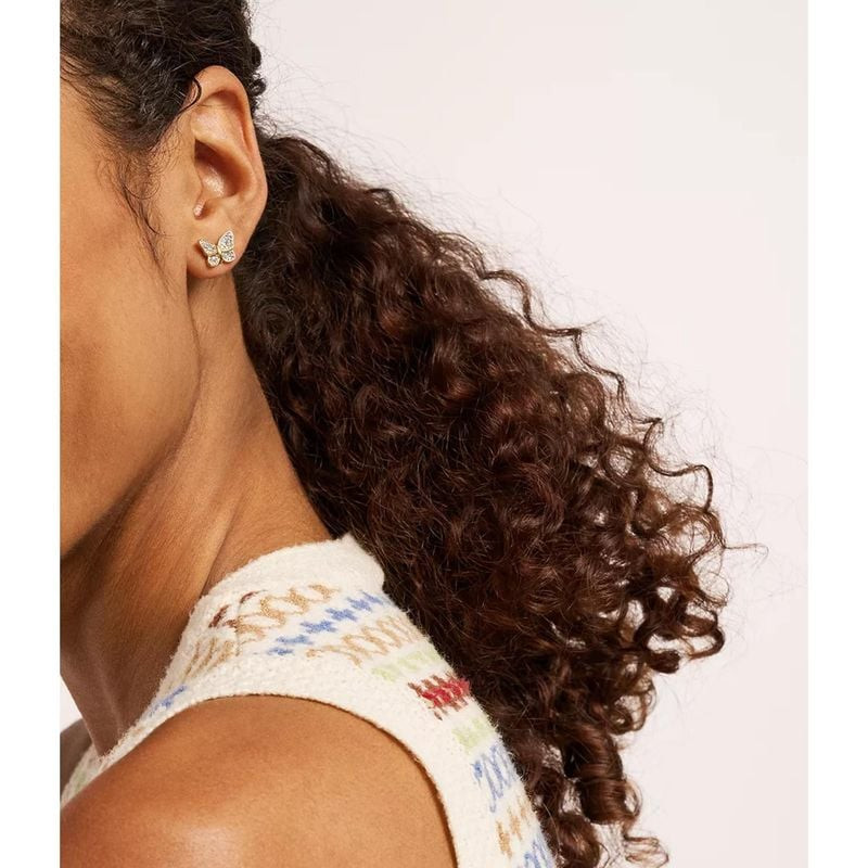 Boucles d'oreilles Puces Fossil Papillon Acier Doré, portées par une femme élégante, motif papillon 