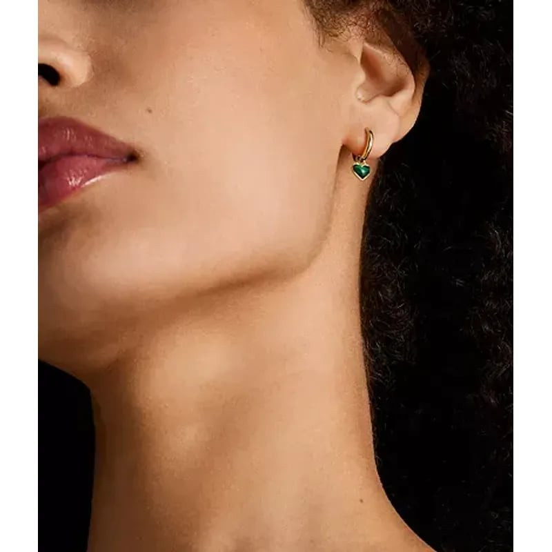 Profil d'une femme portant une créole Fossil Sutton dorée avec un pendentif cœur en malachite verte