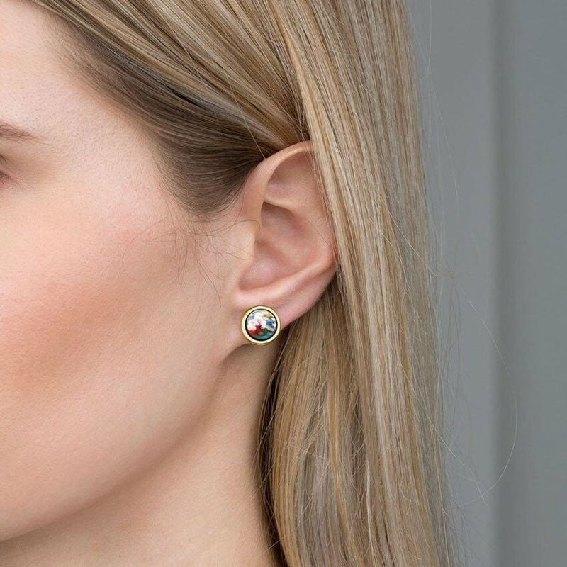 Boucle d'oreille FREYWILLE Cabochon en émail portée sur l'oreille d'une femme blonde, gros plan de p