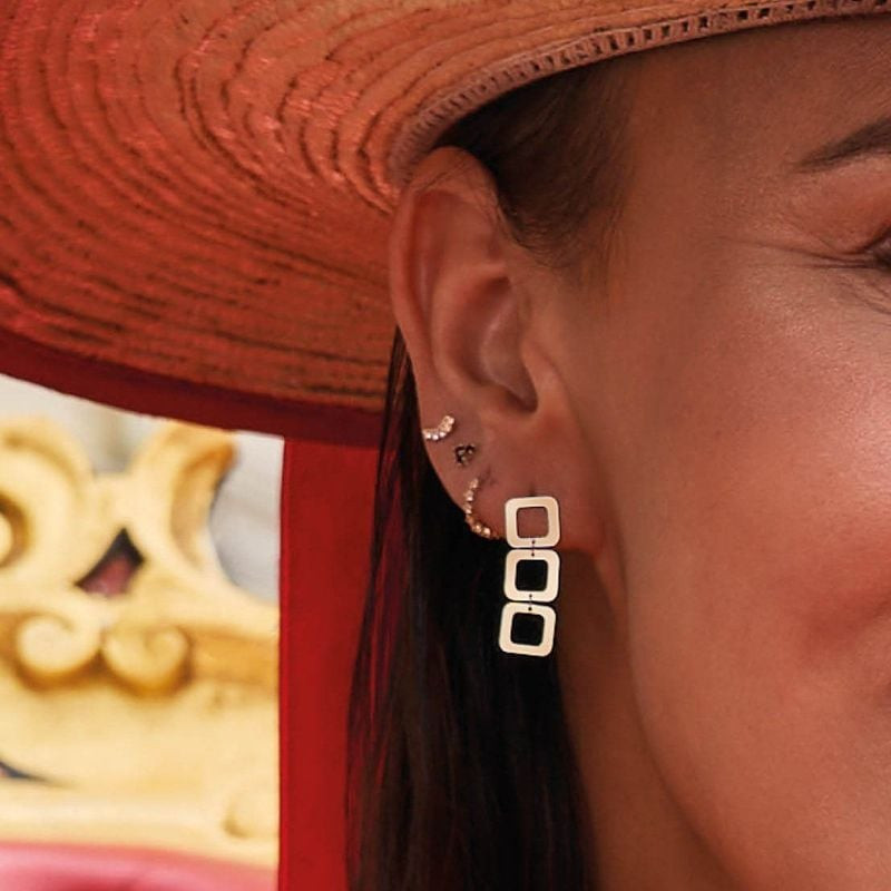Mannequin portant des clous d'oreilles Jackie Gold Laguna en or 14 carats et un chapeau de paille ro