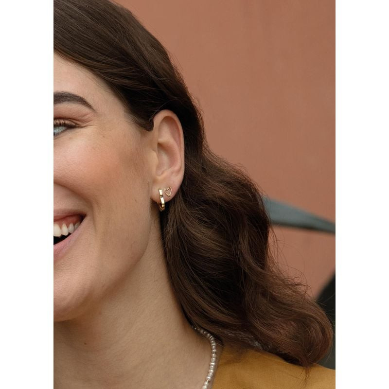 Femme souriante portant une boucle d'oreille clou en or 14 carats cœur torsadé à l'oreille gauche