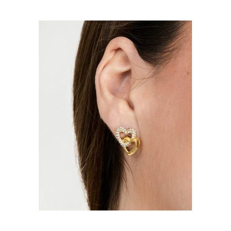 Gros plan d'une boucle d'oreille puce Guess Beloved en acier doré à cœur serti de cristaux scintilla