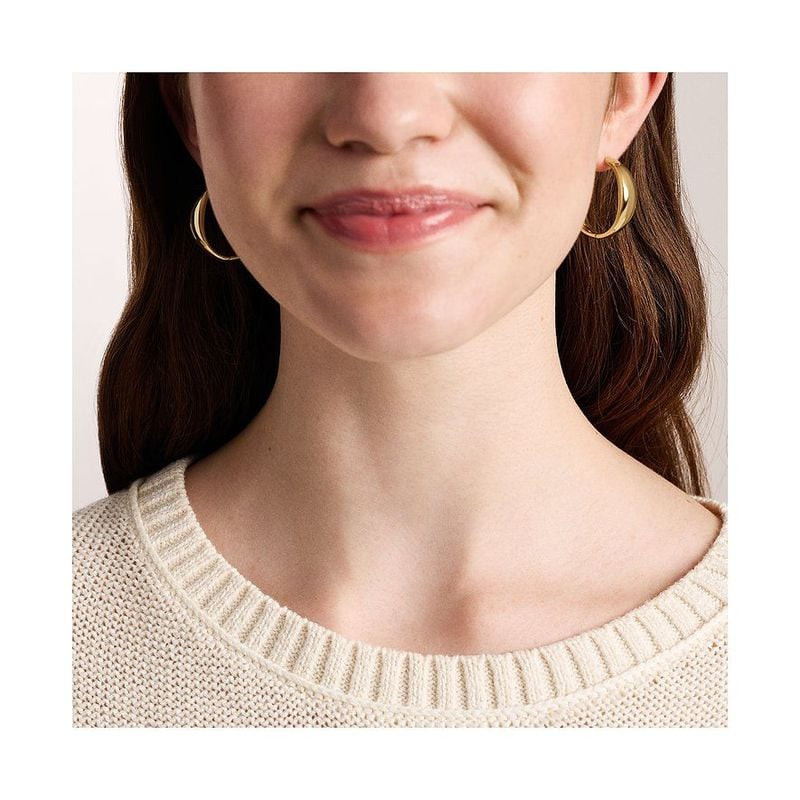 Femme portant les Boucles d'oreilles Créoles Fossil Ellis Acier Doré, look élégant et lumineux.