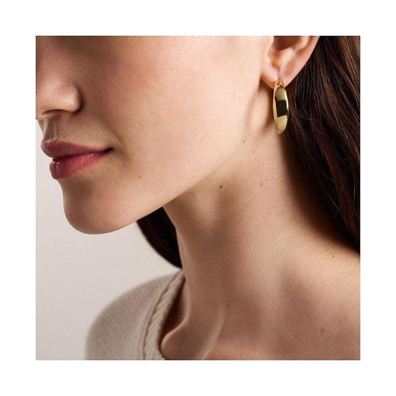 Boucles d'oreilles Créoles Fossil Ellis Acier Doré portées par une femme, look élégant et lumineux.