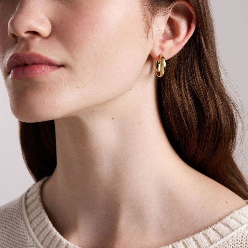 Boucles d'Oreilles Créoles Fossil Ellis Ronde Acier Doré portées par un mannequin dans un cadre élég